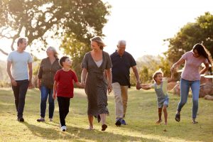 Multi-Generation Family Walking In Countryside Against Flaring Sun
